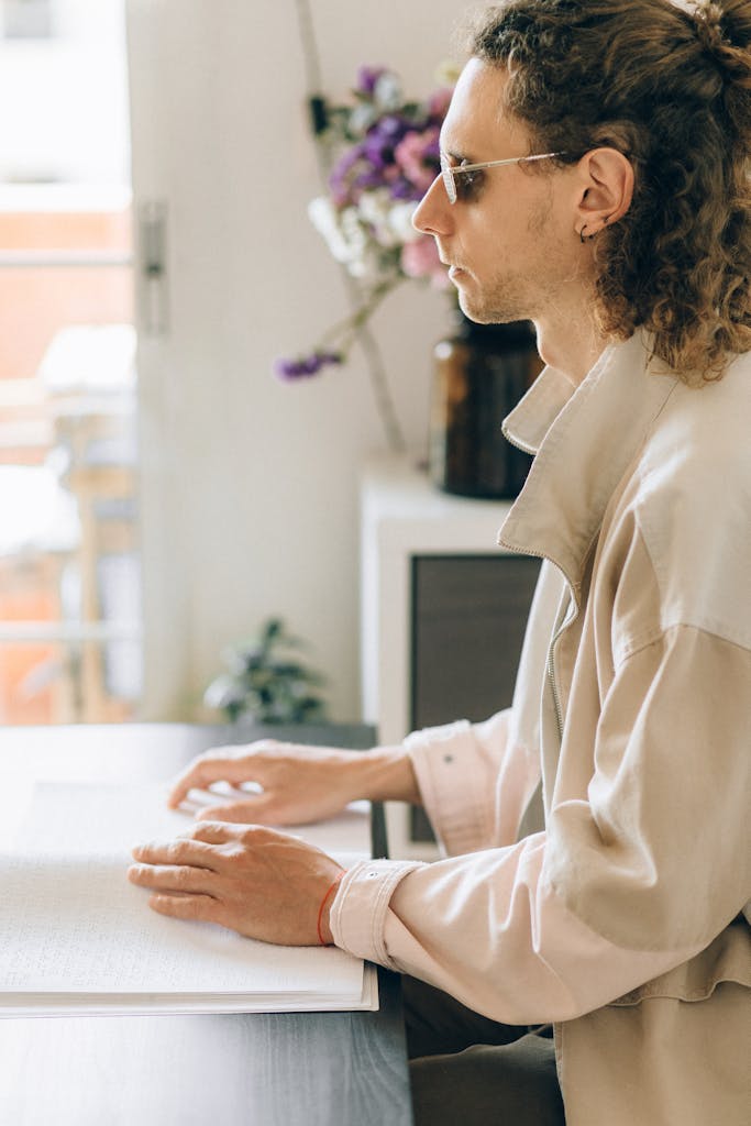 A Side View of a Man Sitting while Touching a Braille